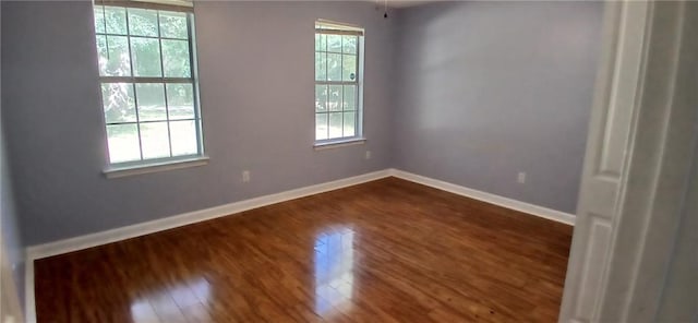 spare room with dark hardwood / wood-style flooring and plenty of natural light