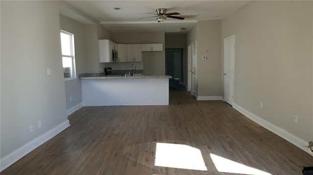 kitchen featuring ceiling fan, light stone counters, dark hardwood / wood-style flooring, kitchen peninsula, and white cabinets