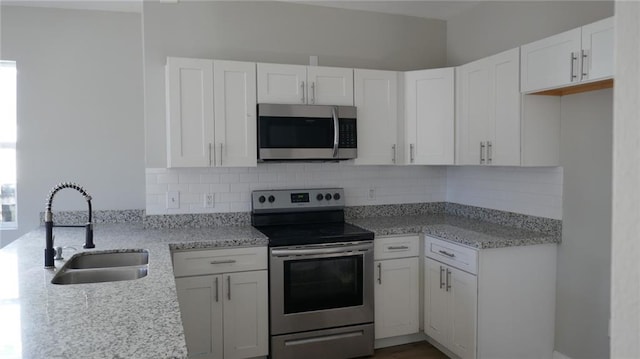 kitchen with light stone countertops, sink, tasteful backsplash, white cabinets, and appliances with stainless steel finishes