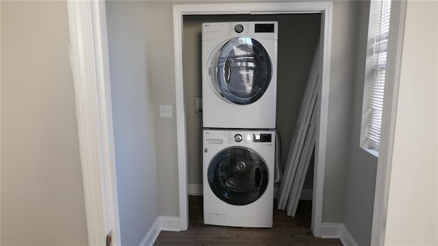 laundry area with dark hardwood / wood-style flooring, plenty of natural light, and stacked washer / dryer