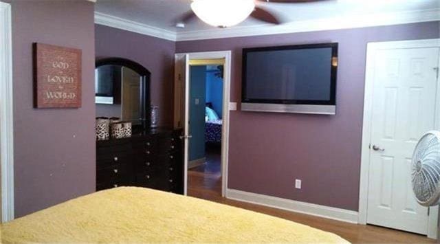 bedroom with hardwood / wood-style floors, ceiling fan, and ornamental molding