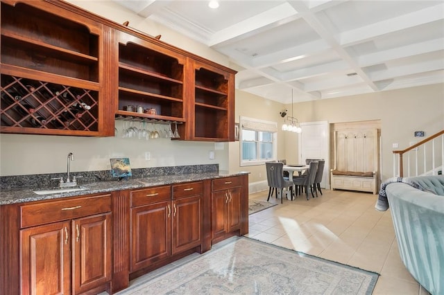 kitchen featuring coffered ceiling, sink, decorative light fixtures, dark stone countertops, and beamed ceiling