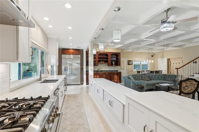 kitchen featuring high quality appliances, coffered ceiling, white cabinets, sink, and extractor fan