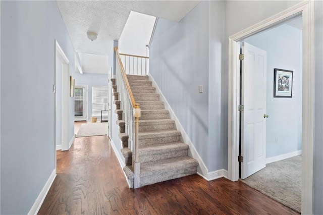 stairs with wood-type flooring and a textured ceiling