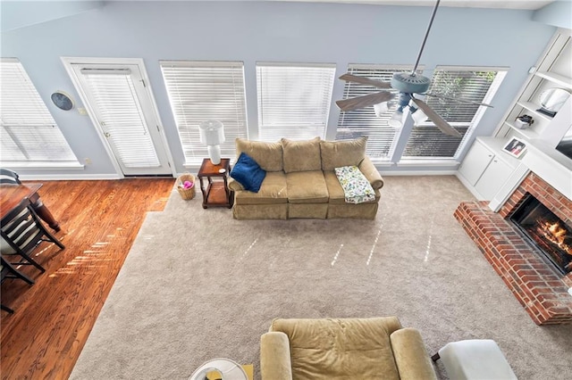 living room with a brick fireplace, ceiling fan, light wood-type flooring, and lofted ceiling