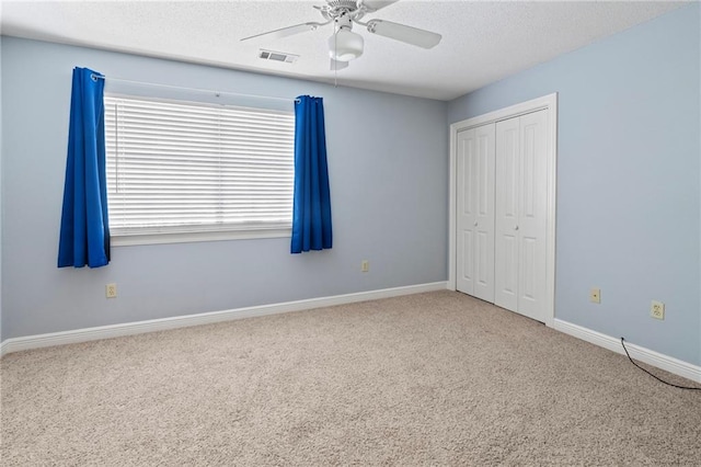 unfurnished bedroom with carpet flooring, a textured ceiling, a closet, and ceiling fan