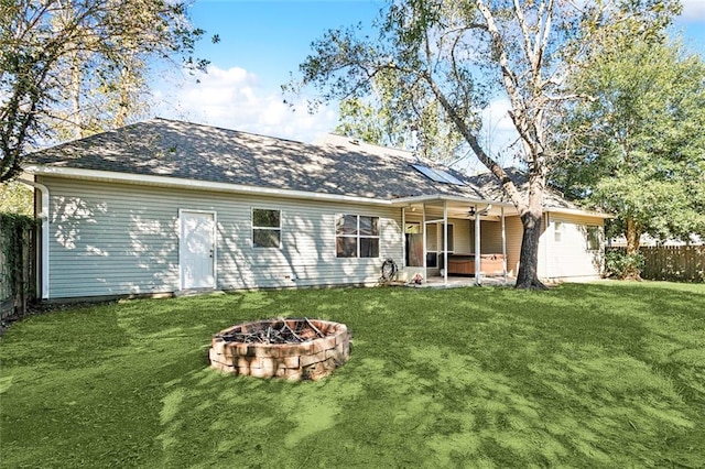 back of property with a fire pit, ceiling fan, a patio area, and a yard