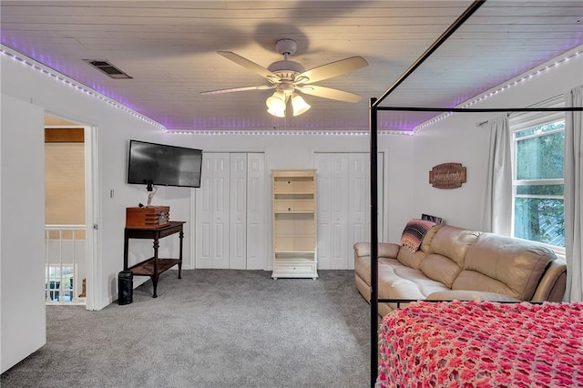 carpeted bedroom featuring ceiling fan, wood ceiling, and two closets