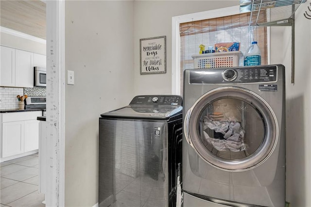 laundry area with washer and clothes dryer, light tile patterned floors, and crown molding