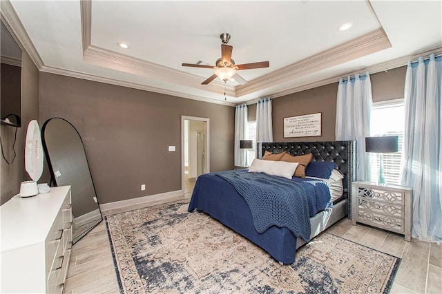 bedroom with a raised ceiling, multiple windows, crown molding, and ceiling fan