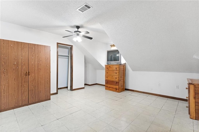 bonus room featuring lofted ceiling, visible vents, ceiling fan, a textured ceiling, and baseboards