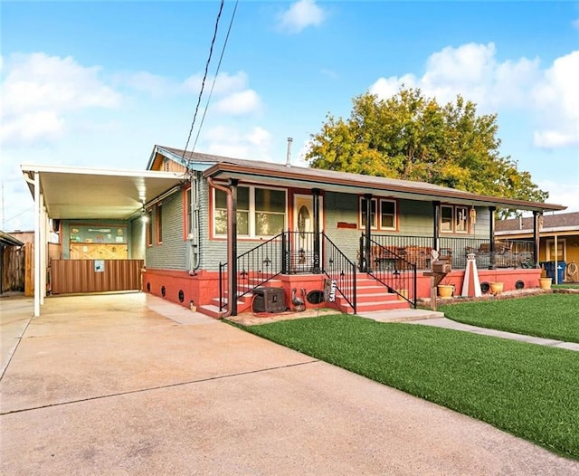 ranch-style house featuring covered porch, a front yard, and a carport