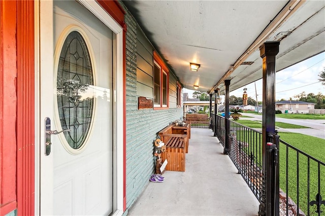 view of exterior entry featuring a yard and a porch