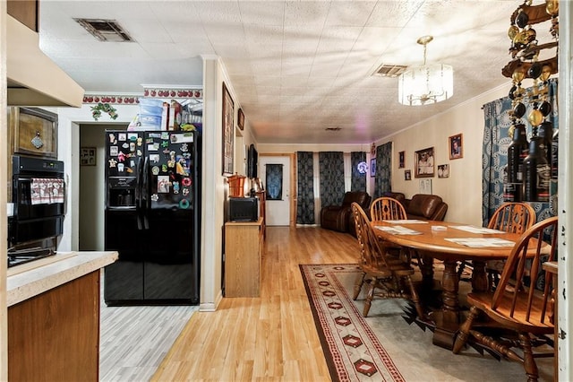 dining area with an inviting chandelier, light hardwood / wood-style flooring, and crown molding