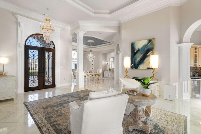 entryway with french doors, decorative columns, crown molding, and a notable chandelier