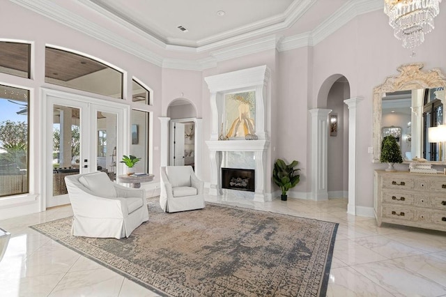 living room with french doors, an inviting chandelier, a towering ceiling, a fireplace, and ornamental molding