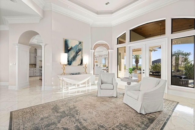 living area with a high ceiling, ornate columns, french doors, and crown molding