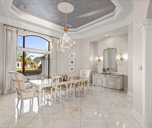 dining area featuring a tray ceiling, ornate columns, a chandelier, and ornamental molding