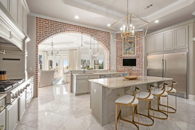 kitchen with light stone counters, a center island, decorative light fixtures, and appliances with stainless steel finishes