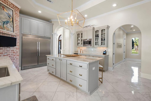 kitchen featuring built in appliances, a kitchen island, crown molding, and tasteful backsplash