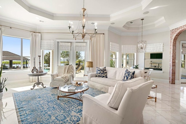 living room with a tray ceiling, an inviting chandelier, and ornamental molding