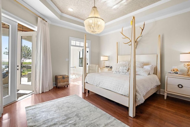 bedroom with dark wood-type flooring, a raised ceiling, crown molding, a chandelier, and access to outside