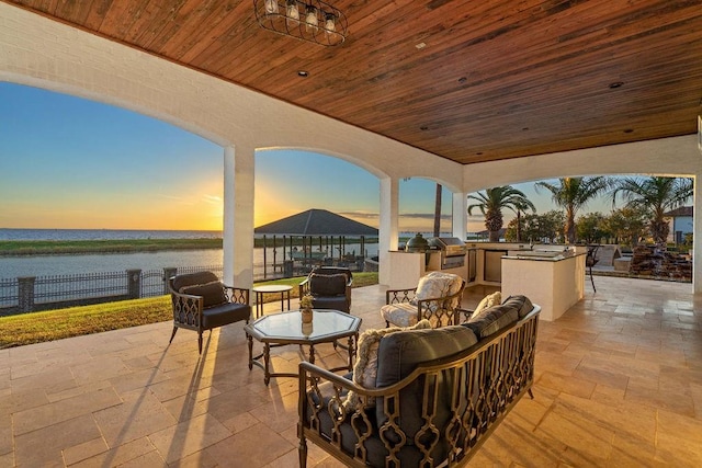 patio terrace at dusk with a water view, area for grilling, and grilling area