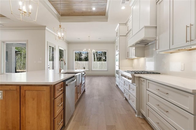 kitchen with a chandelier, white cabinets, light countertops, appliances with stainless steel finishes, and a large island with sink