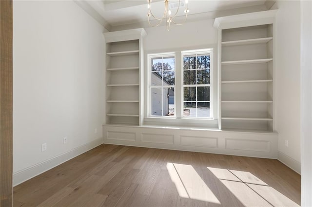 interior space featuring baseboards, an inviting chandelier, built in features, and light wood-style floors