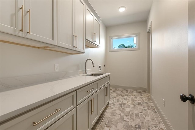 washroom with a sink, hookup for a washing machine, cabinet space, and baseboards