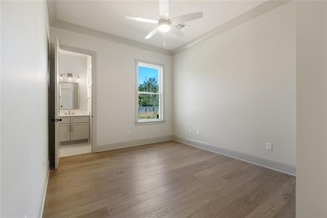 unfurnished bedroom featuring connected bathroom, a sink, visible vents, baseboards, and light wood finished floors