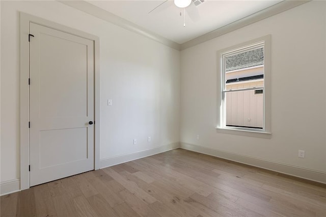 empty room featuring light wood-style floors, baseboards, and a ceiling fan