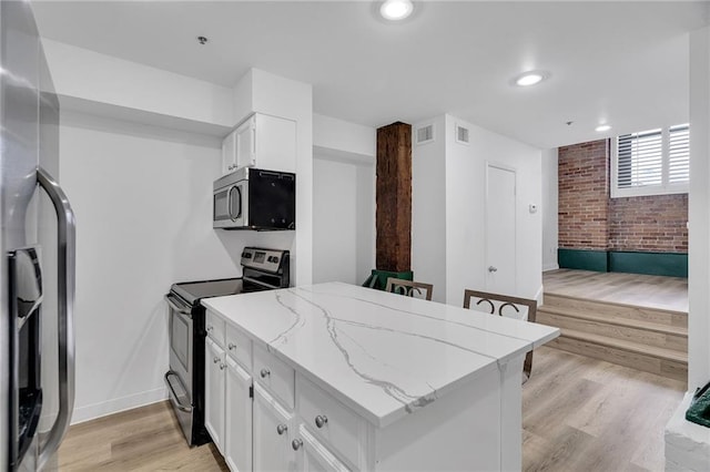 kitchen with light stone countertops, appliances with stainless steel finishes, light hardwood / wood-style floors, and white cabinetry