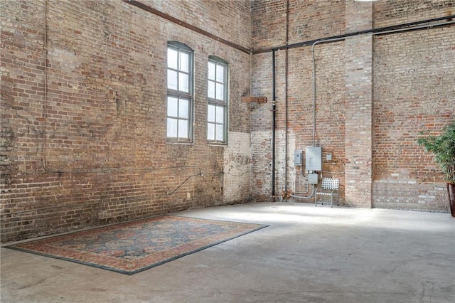 miscellaneous room with a high ceiling, concrete floors, and brick wall