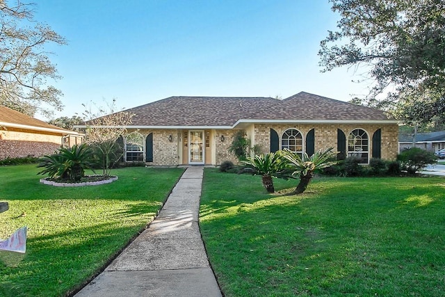 ranch-style home featuring a shingled roof, a front yard, and brick siding