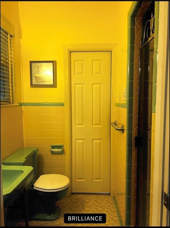 bathroom featuring tile walls, tile patterned floors, and toilet