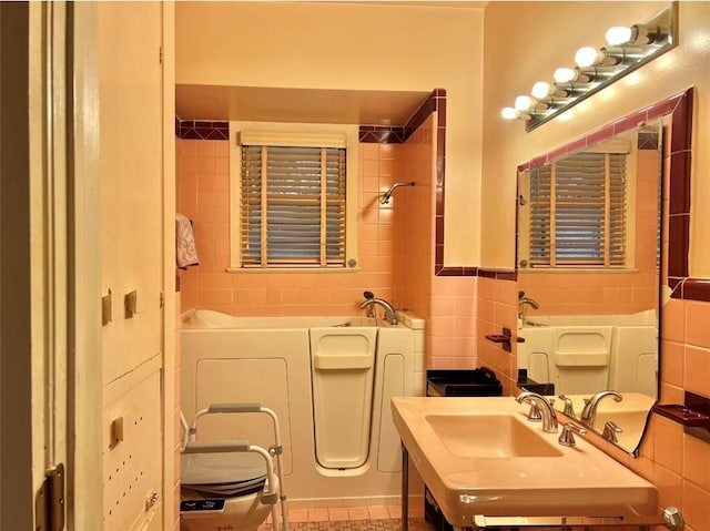 bathroom with toilet, a bathing tub, sink, and tile walls