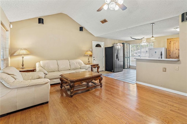 living room featuring a textured ceiling, ceiling fan, light hardwood / wood-style floors, and vaulted ceiling