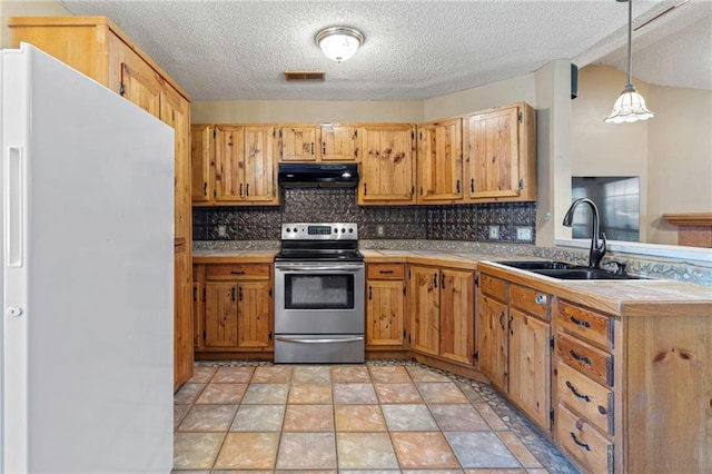 kitchen featuring white refrigerator, sink, hanging light fixtures, electric range, and decorative backsplash