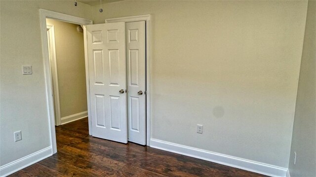 361 Helis Dr, Westwego, LA 70094 - unfurnished bedroom with baseboards, dark wood-style floors, and a closet