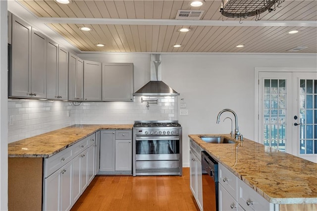 kitchen with stainless steel range, wall chimney range hood, sink, dishwasher, and light hardwood / wood-style floors