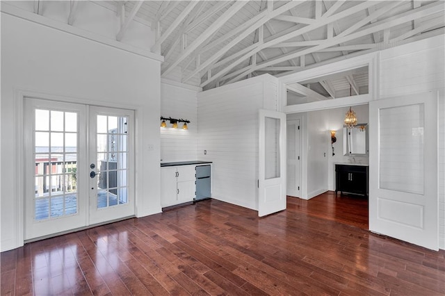 unfurnished living room featuring french doors, dark hardwood / wood-style floors, high vaulted ceiling, and beam ceiling