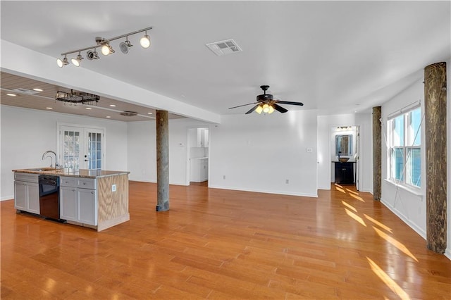 kitchen featuring open floor plan, ceiling fan, a sink, french doors, and light wood-style flooring