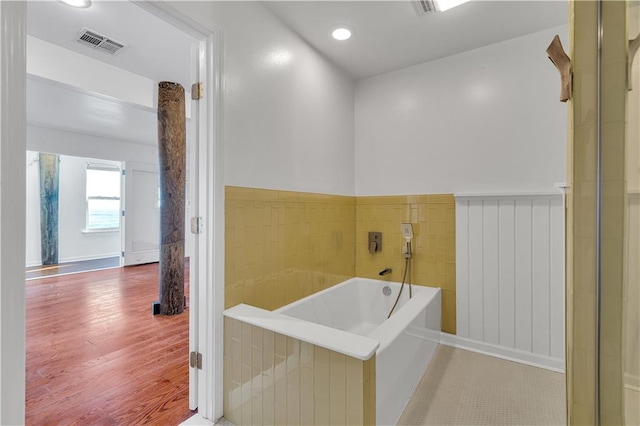 bathroom with a washtub and wood-type flooring