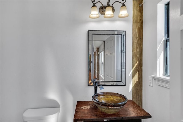 bathroom with a chandelier, toilet, and sink