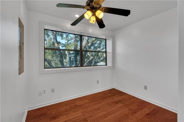 empty room with wood-type flooring, electric panel, and ceiling fan