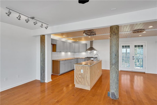 kitchen featuring french doors, wall chimney range hood, light hardwood / wood-style floors, gray cabinets, and wood ceiling