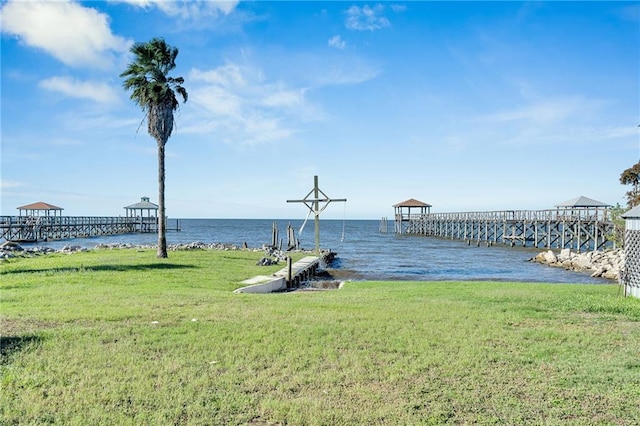 view of dock with a yard and a water view