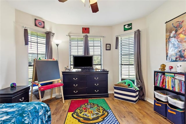 bedroom featuring ceiling fan, light wood-type flooring, and multiple windows