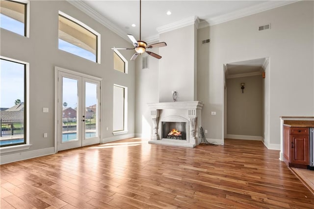 unfurnished living room featuring a high ceiling, light hardwood / wood-style flooring, ceiling fan, and ornamental molding